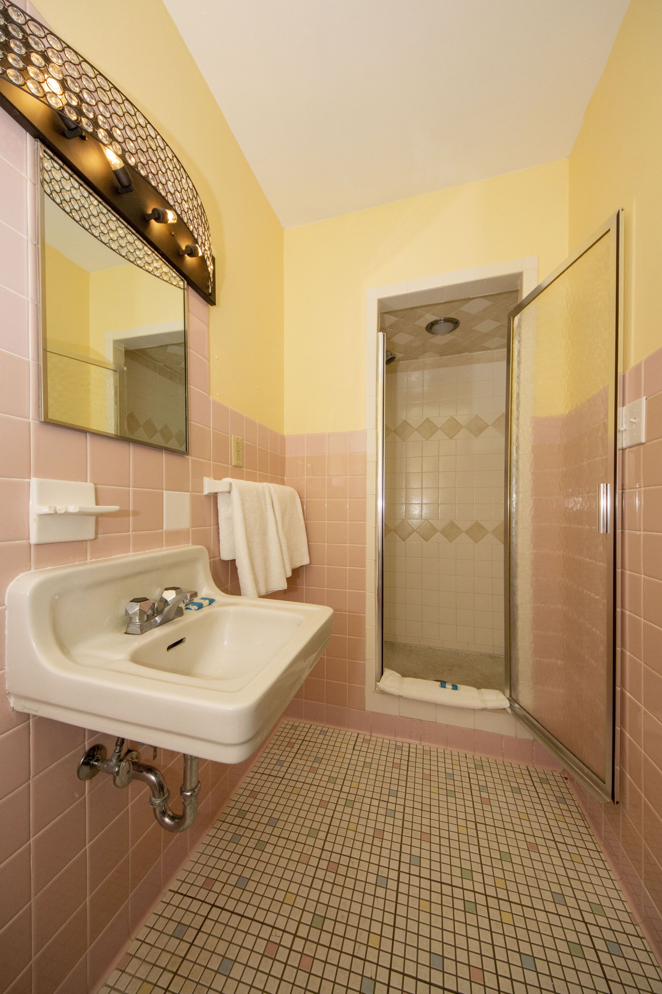 Un baño con lavamanos, espejo y ducha.