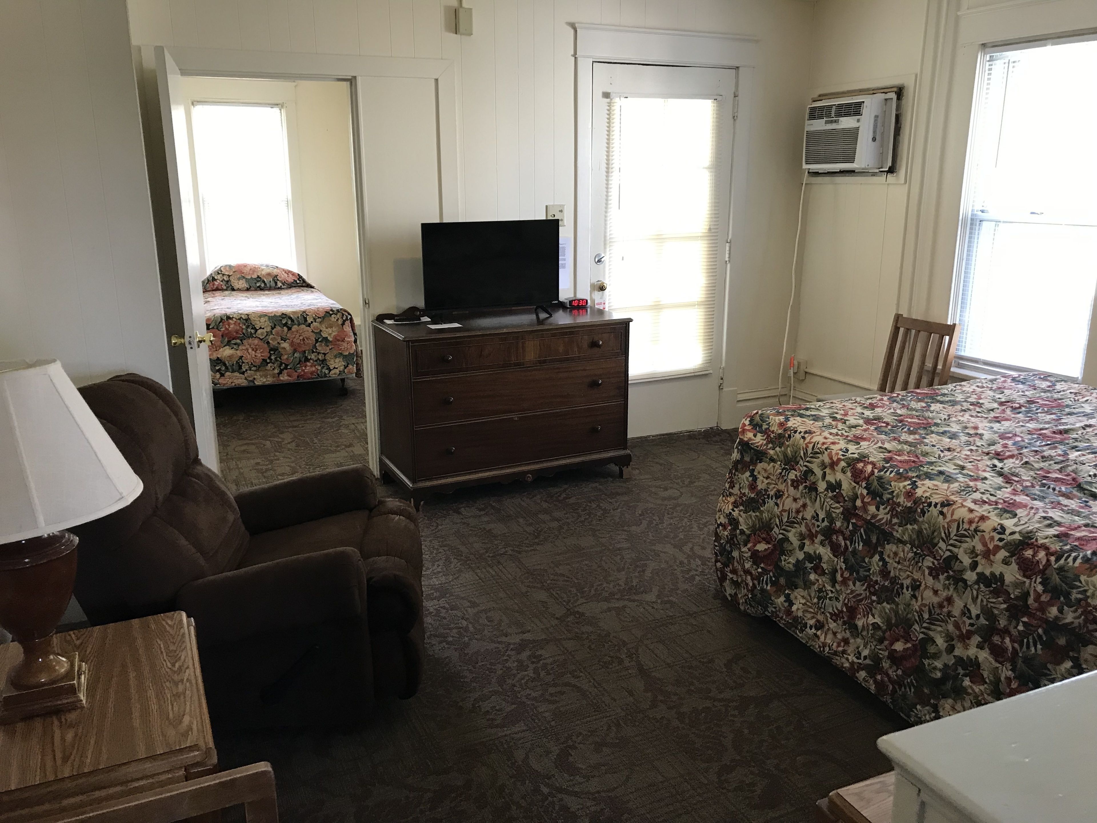 Quarto com cama, penteadeira, cadeira e televisão.