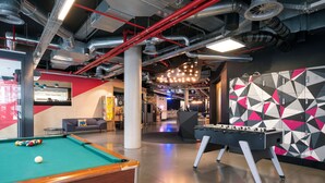 A modern indoor recreational area with a pool table, foosball table, and a colorful geometric wall design. - Pestana Brussels Schuman (Brussels)