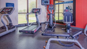 Ein Fitnessraum mit Laufbändern, einem Ergometer und einer Gewichtshalterung.