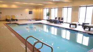 Ein Hallenbad mit Rettungsschwimmerstuhl, Liegestühlen und einer Zimmerpflanze.