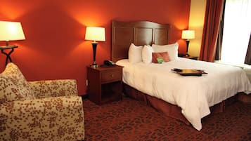 A hotel room with a bed, two bedside lamps, a telephone, a chair, and a patterned carpet.