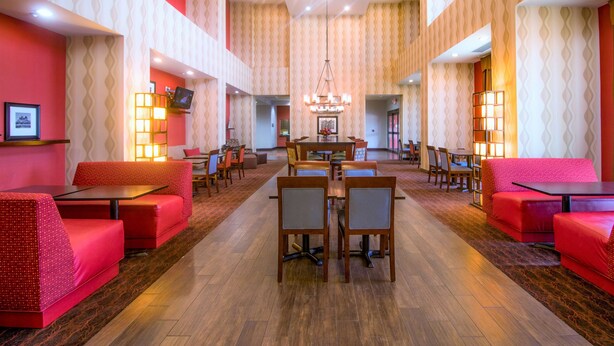 Eine großzügige Lobby mit roter Sitzgelegenheit, einem zentralen Essbereich und gemustertem Wandpapier.