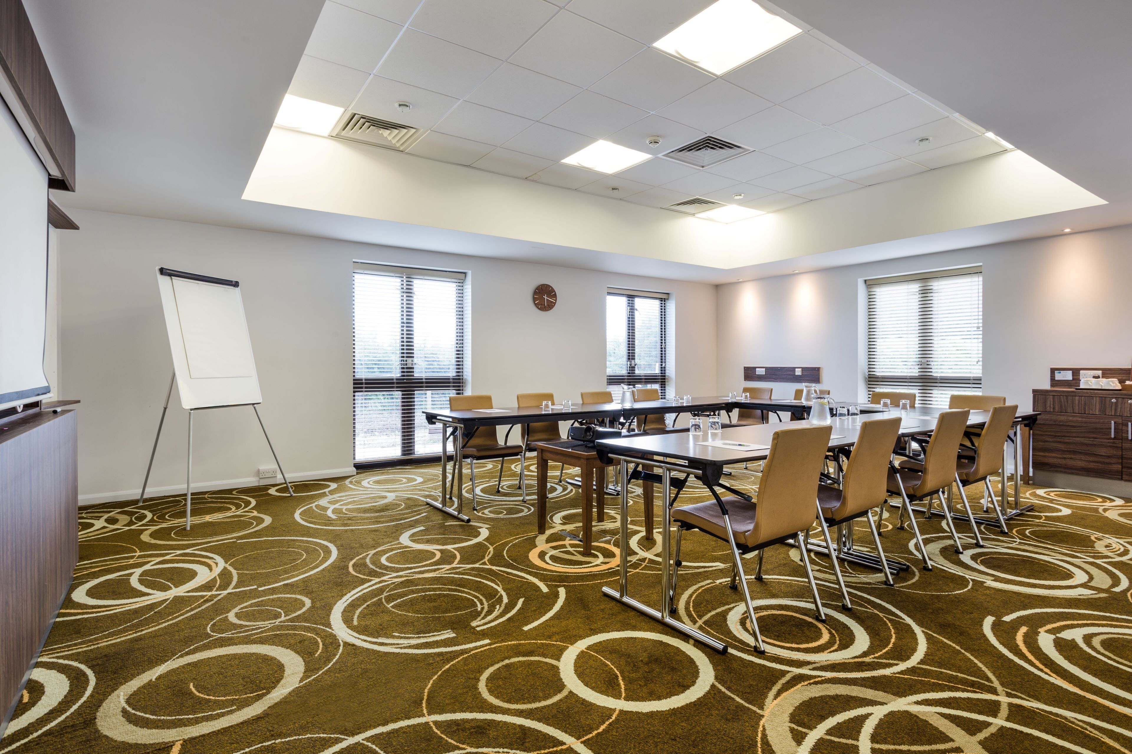 A conference room with a large table, chairs, a whiteboard, and a clock on the wall.