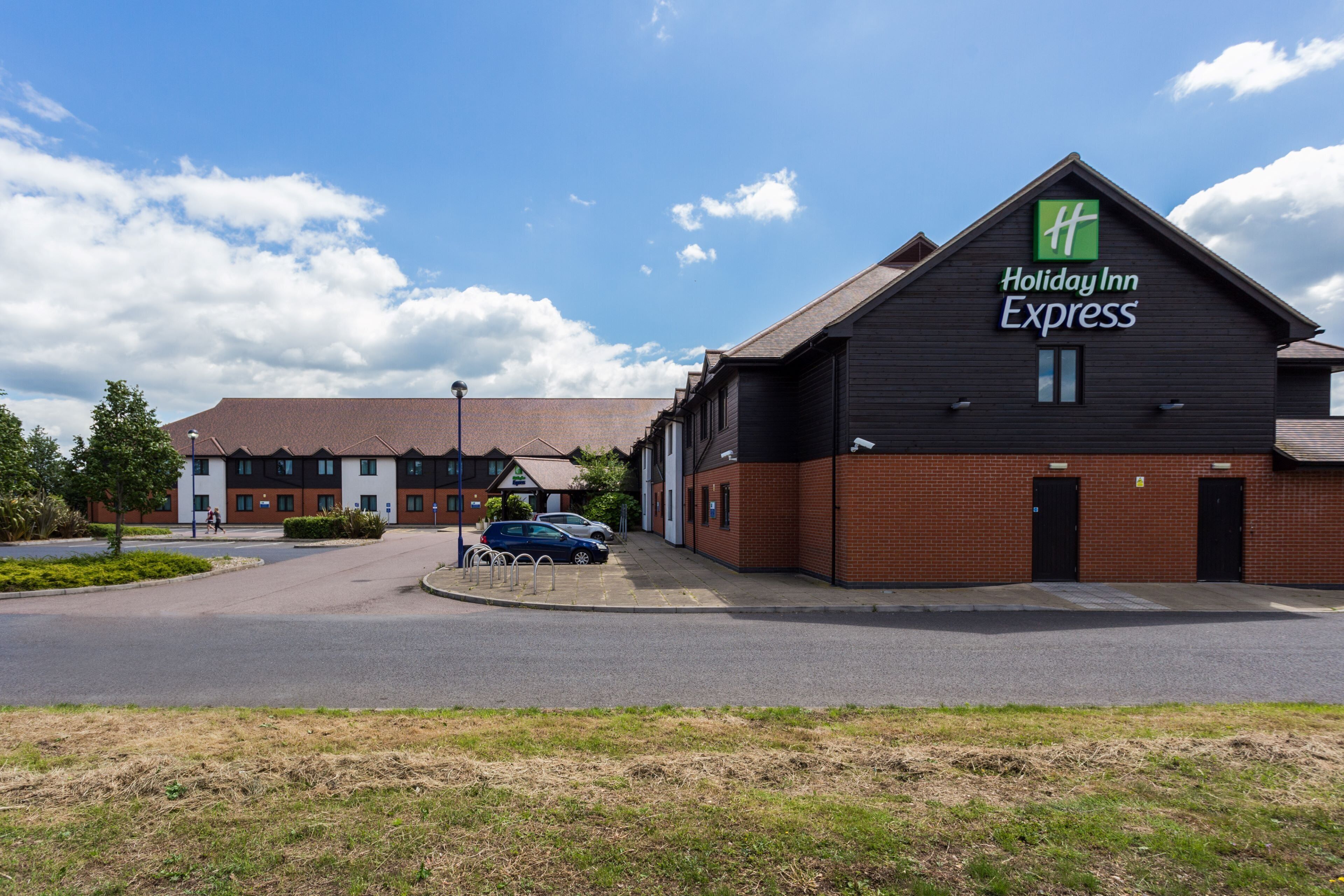 A Holiday Inn Express building with a brick facade, a parking lot, and a clear sky.