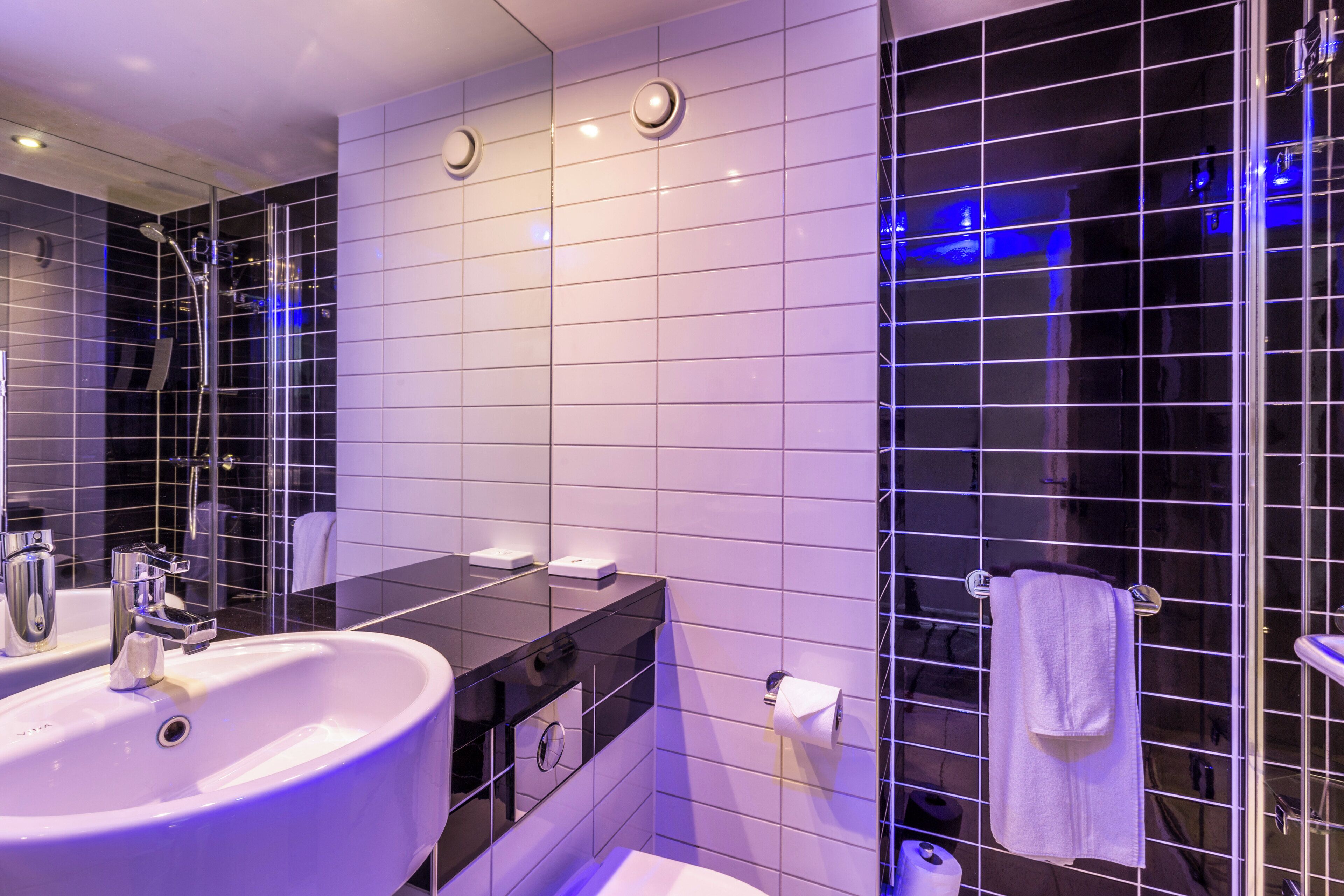 A modern bathroom with a large sink, mirror, and black vanity.