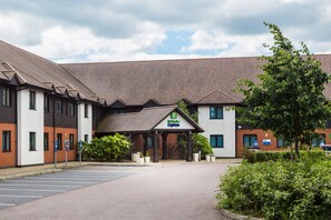 A hotel with a covered entrance, multiple parking spaces, and a clear sky. - Holiday Inn Express Colchester by IHG (Colchester)