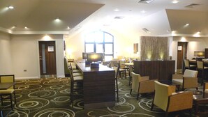 A hotel lobby with a reception desk, seating area, and a large window. - Holiday Inn Express Colchester by IHG (Colchester)