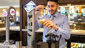 A bartender pouring a drink from a tap labeled 'Stella Artois' into a glass. - Holiday Inn Express Colchester by IHG (Colchester)