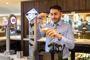 A bartender pouring a drink from a tap labeled 'Stella Artois' into a glass. - Holiday Inn Express Colchester by IHG (Colchester)