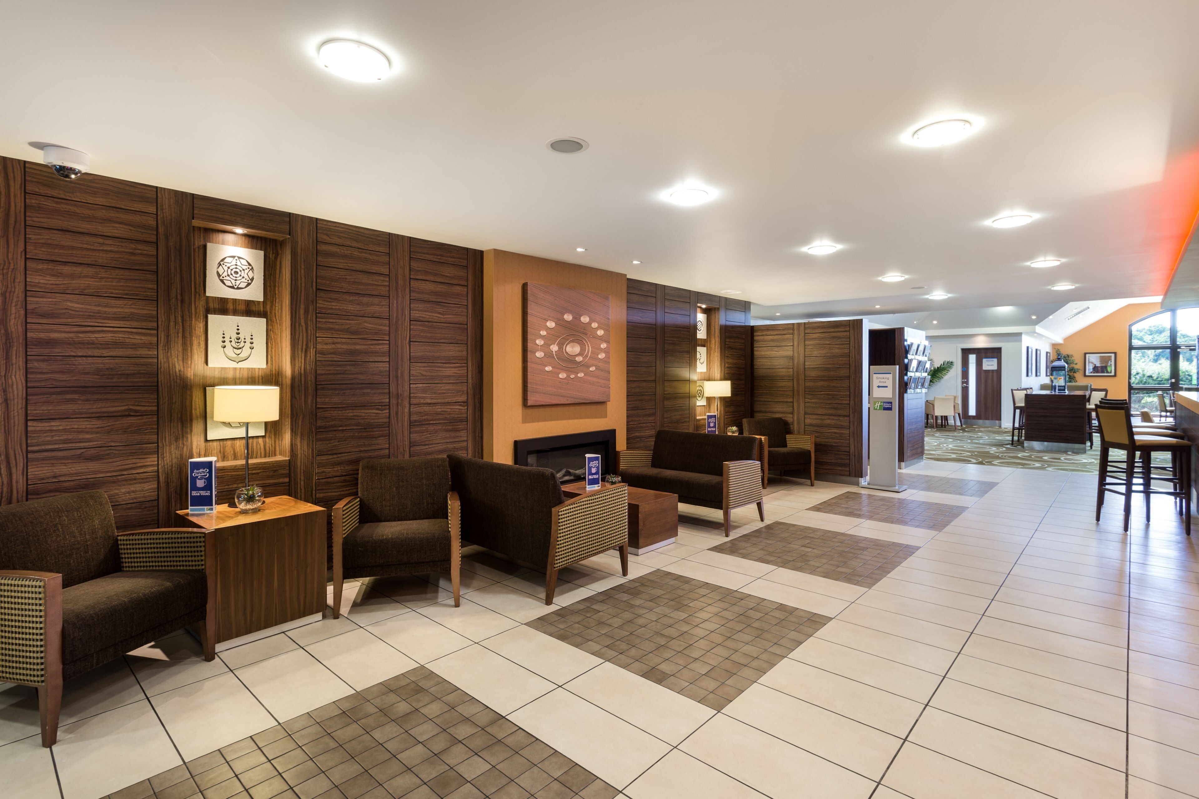 A hotel lobby with a reception desk, seating area, and a view of the outdoor area.