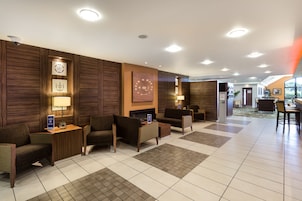 Un vestíbulo de hotel con mostrador de recepción, zona de estar y vistas al exterior.