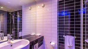 A modern bathroom with a large sink, mirror, and a glass shower enclosure. - Holiday Inn Express Colchester by IHG (Colchester)