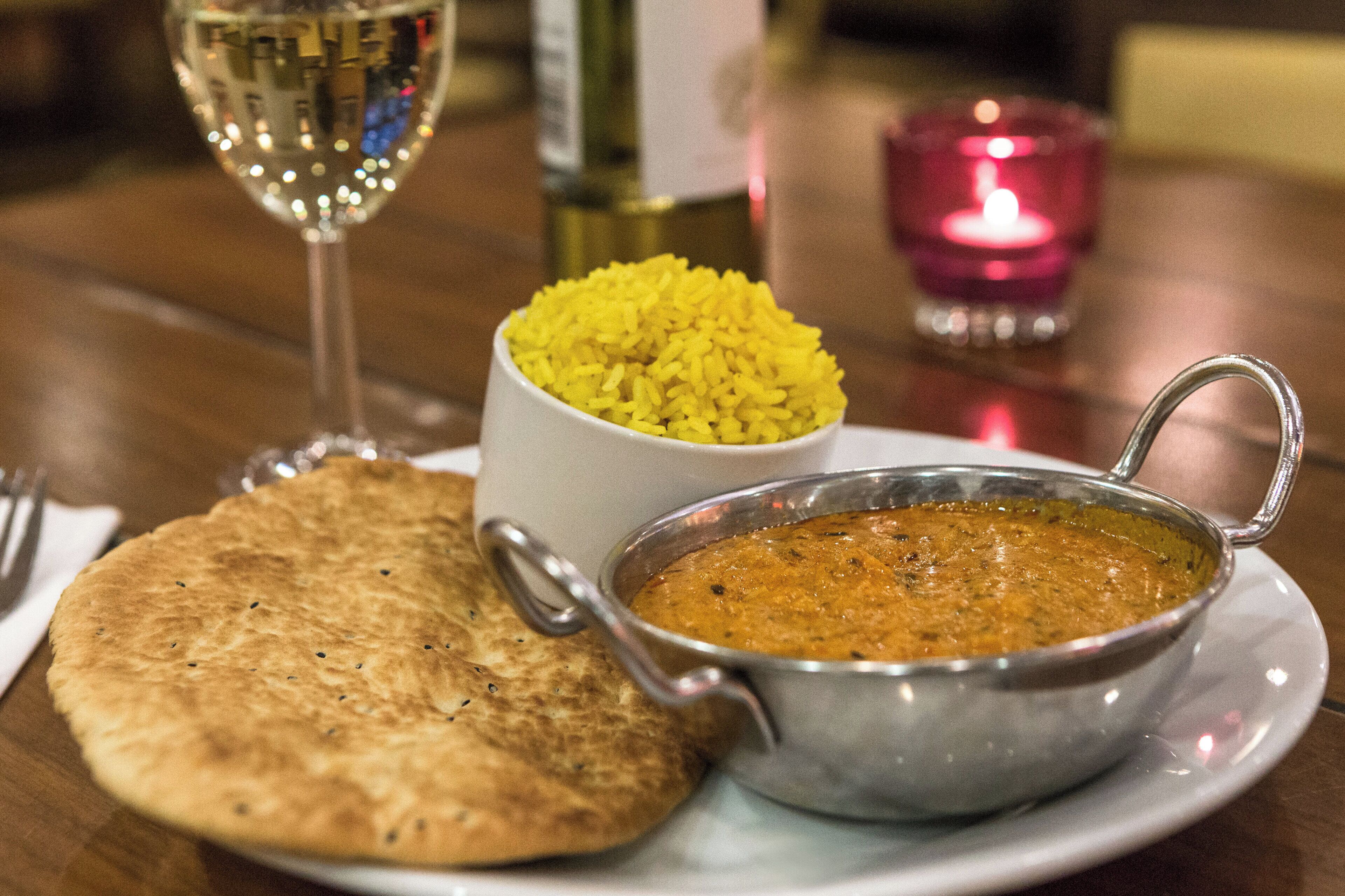 A meal consisting of a bowl of yellow rice, a bowl of brown soup, and a piece of flatbread on a plate.