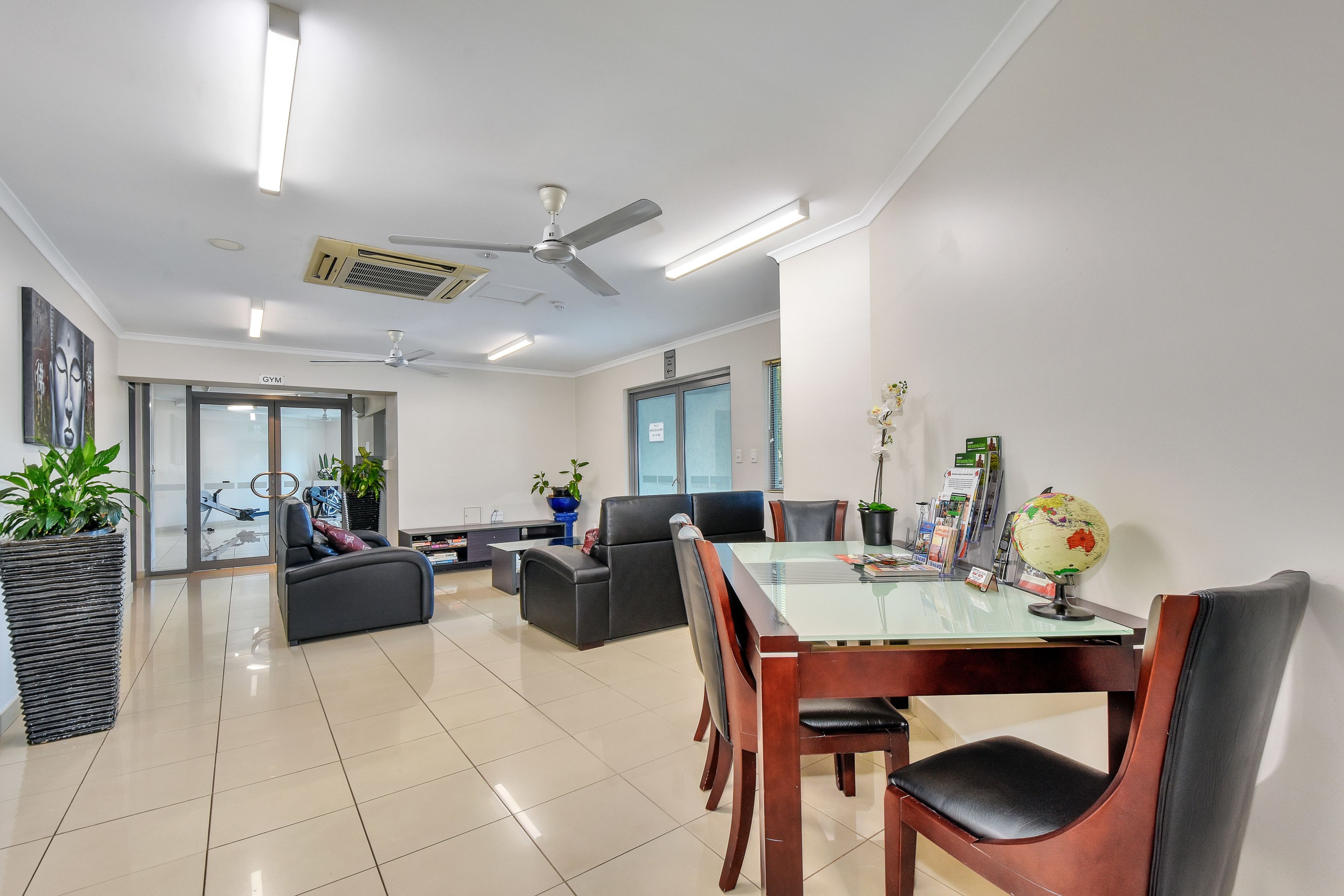 Uma sala de estar moderna com uma mesa de jantar de vidro, sofás de couro e um ventilador de teto.