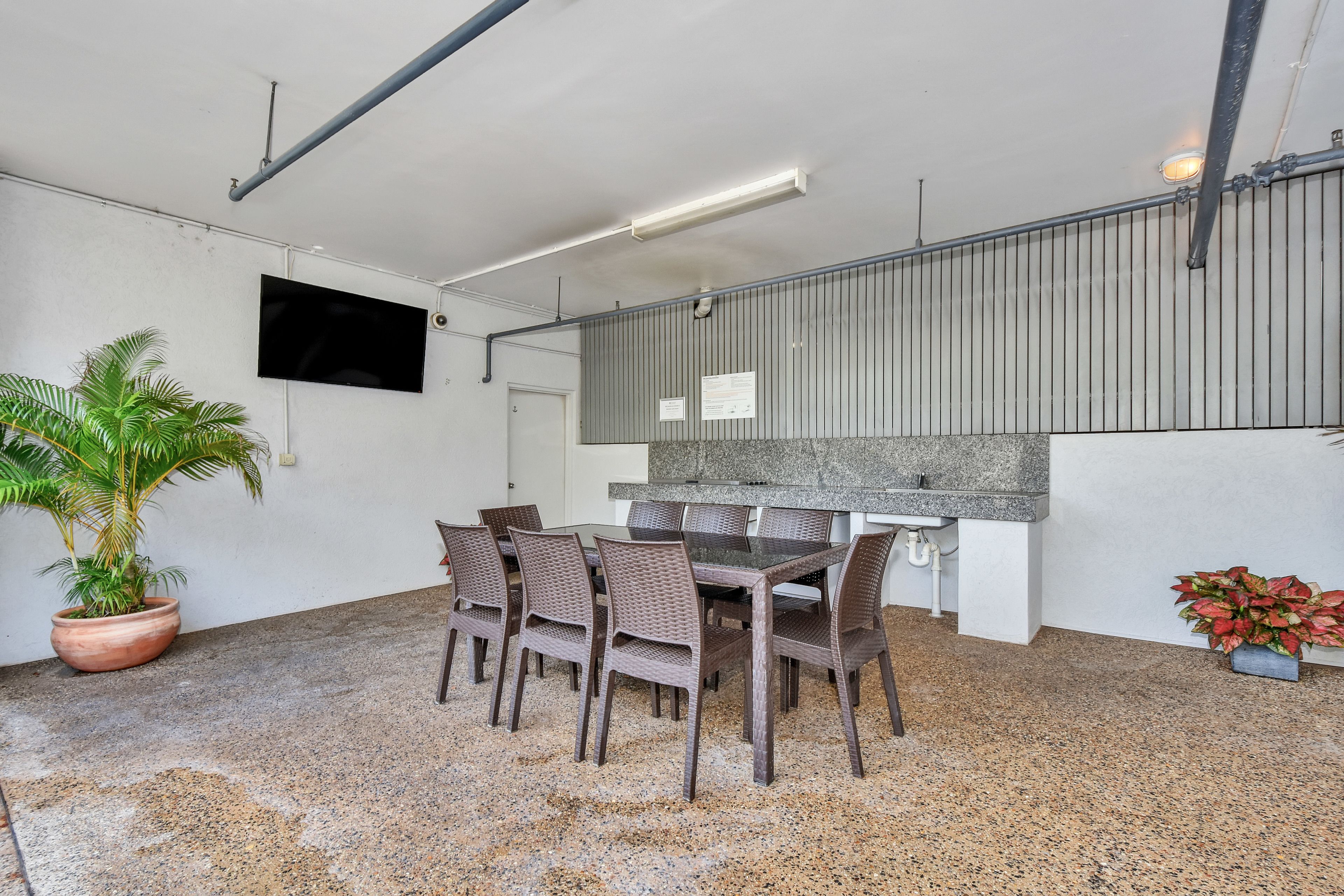 A dining area with a table and chairs, a potted plant, and a kitchen counter.