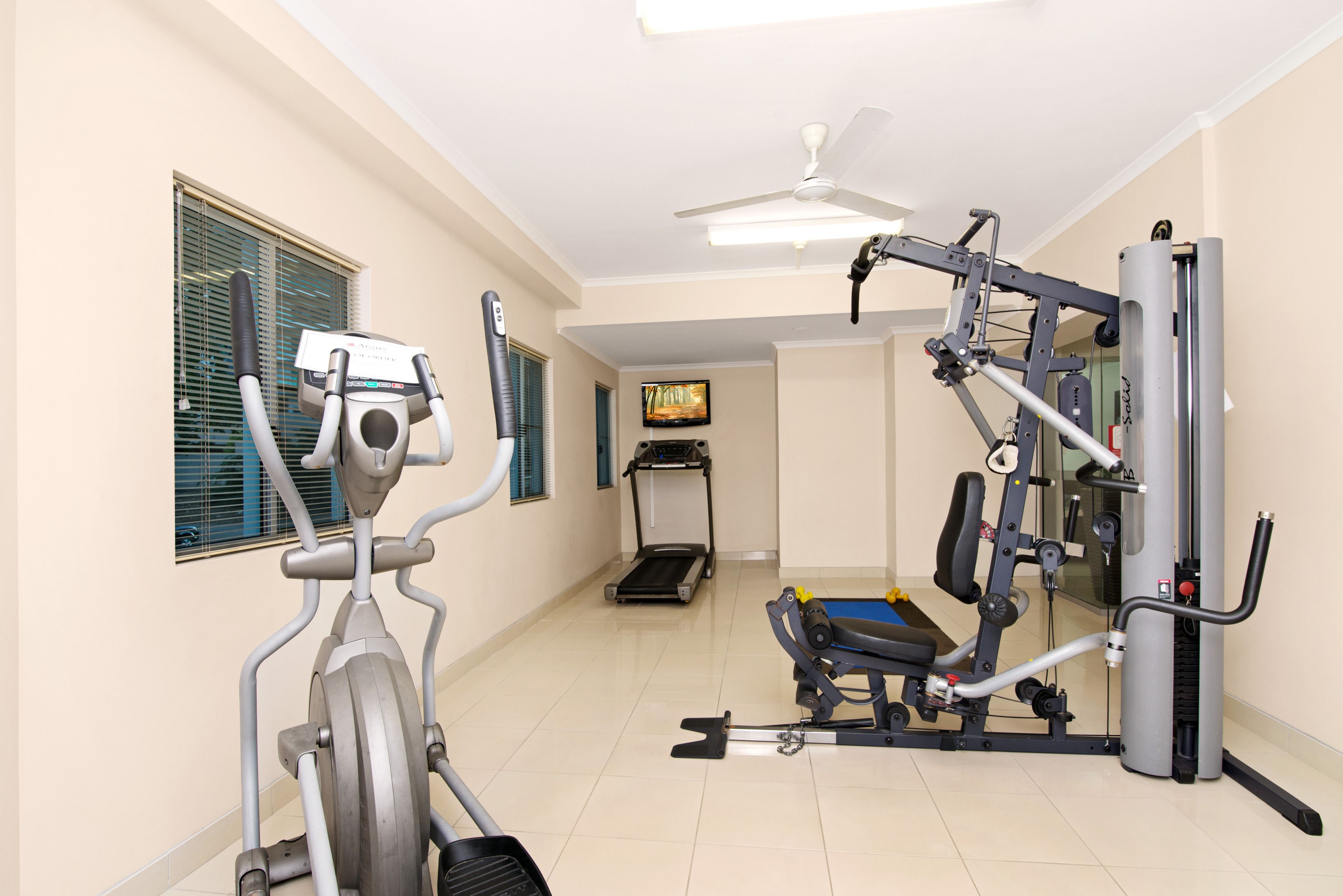 A home gym with an elliptical, a treadmill, and a weight machine.