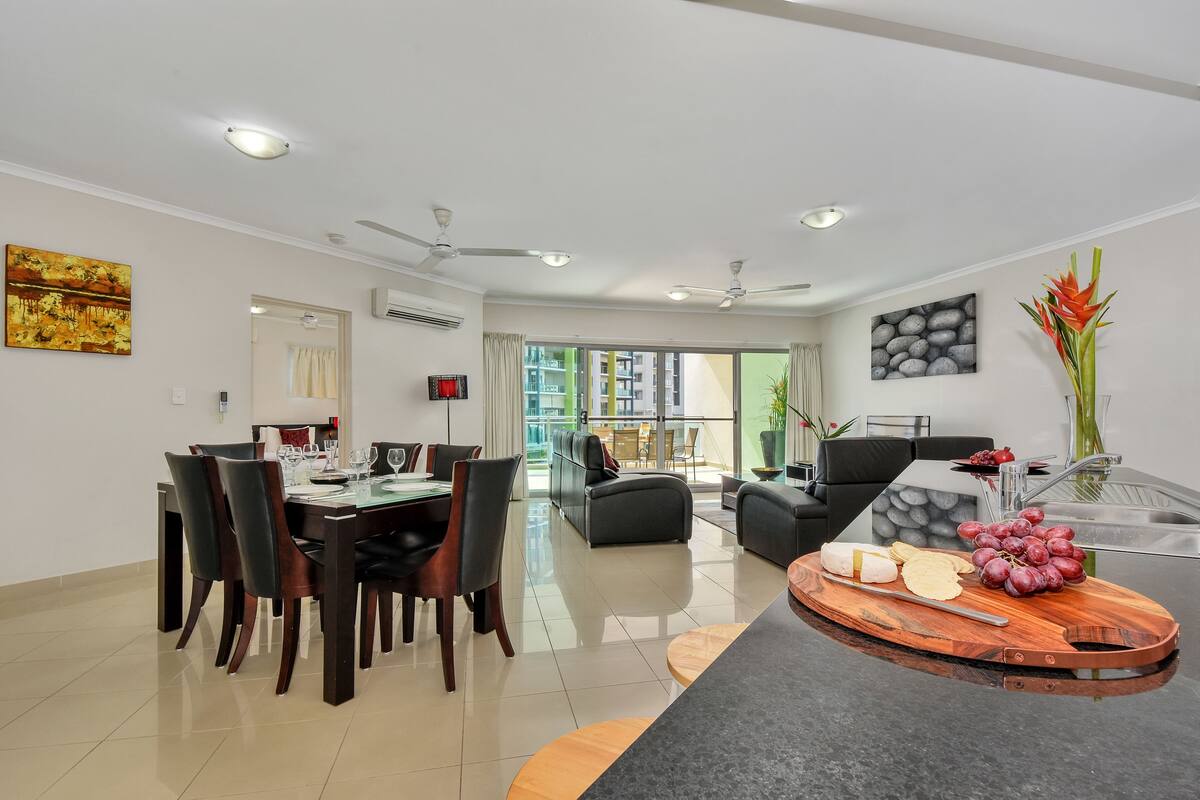 A modern living room with a dining area, a kitchen, and a balcony with a view.