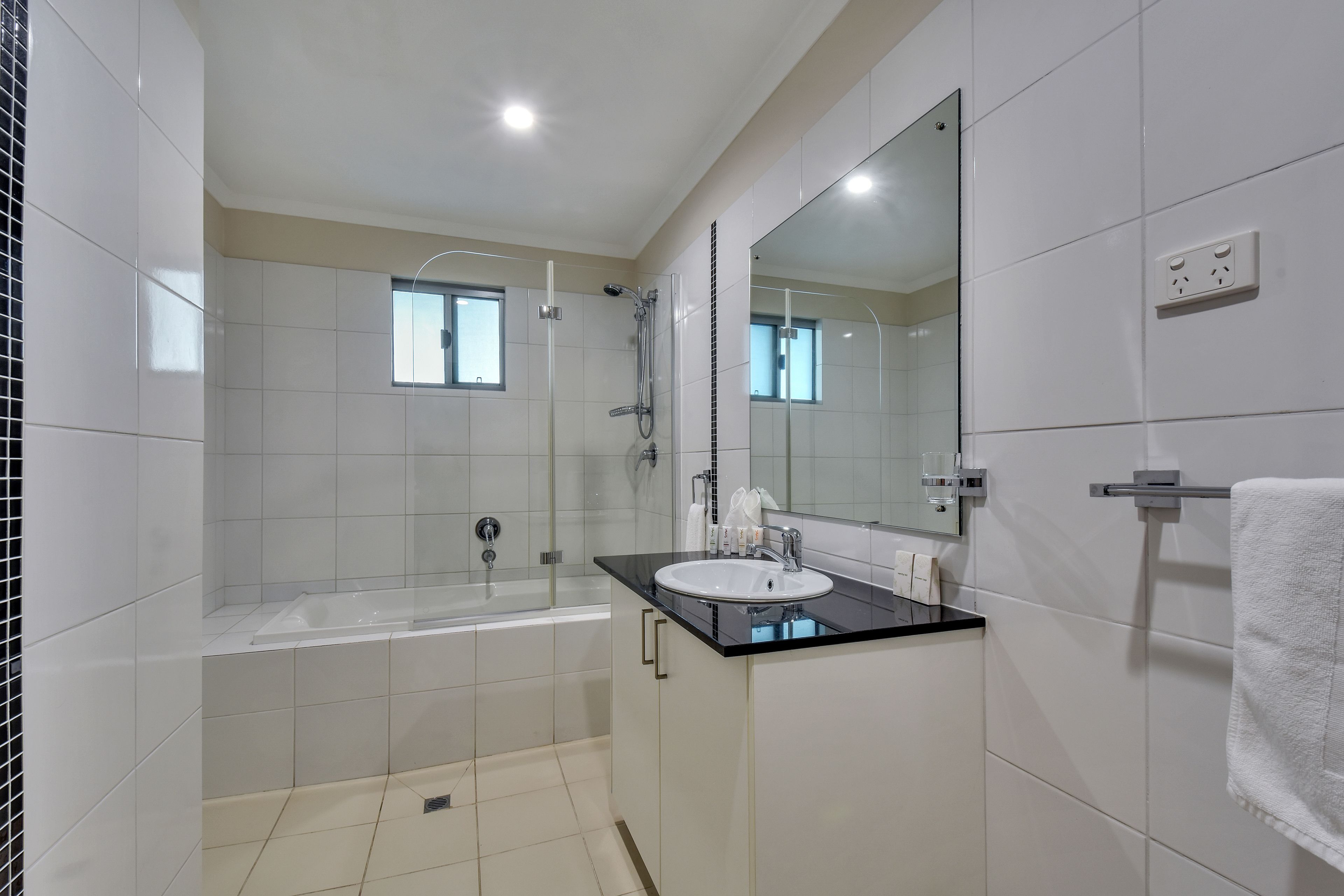 A modern bathroom with a bathtub, a sink, and a large mirror.