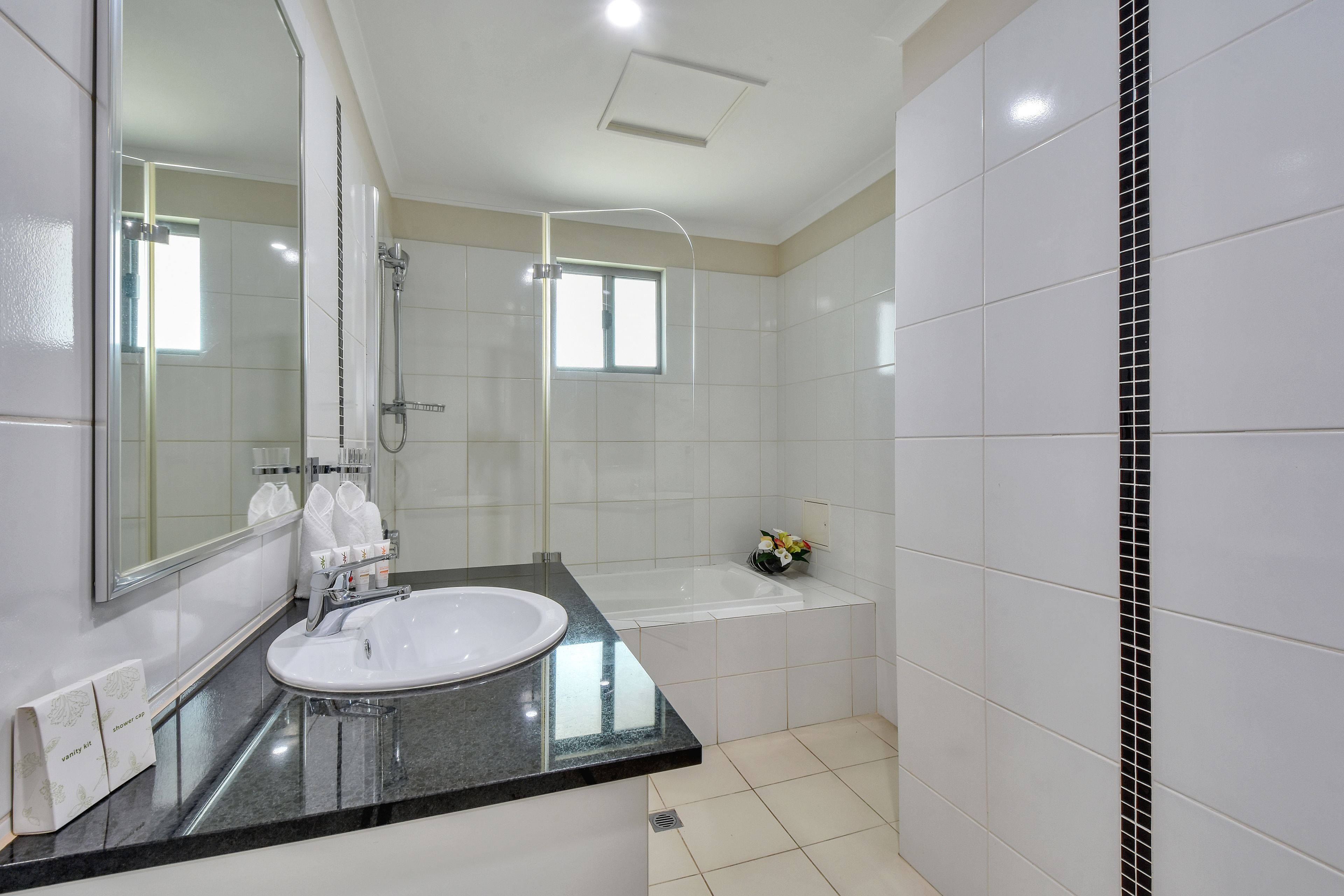 Un baño moderno con un lavamanos blanco, un espejo grande, una ducha y una bañera.