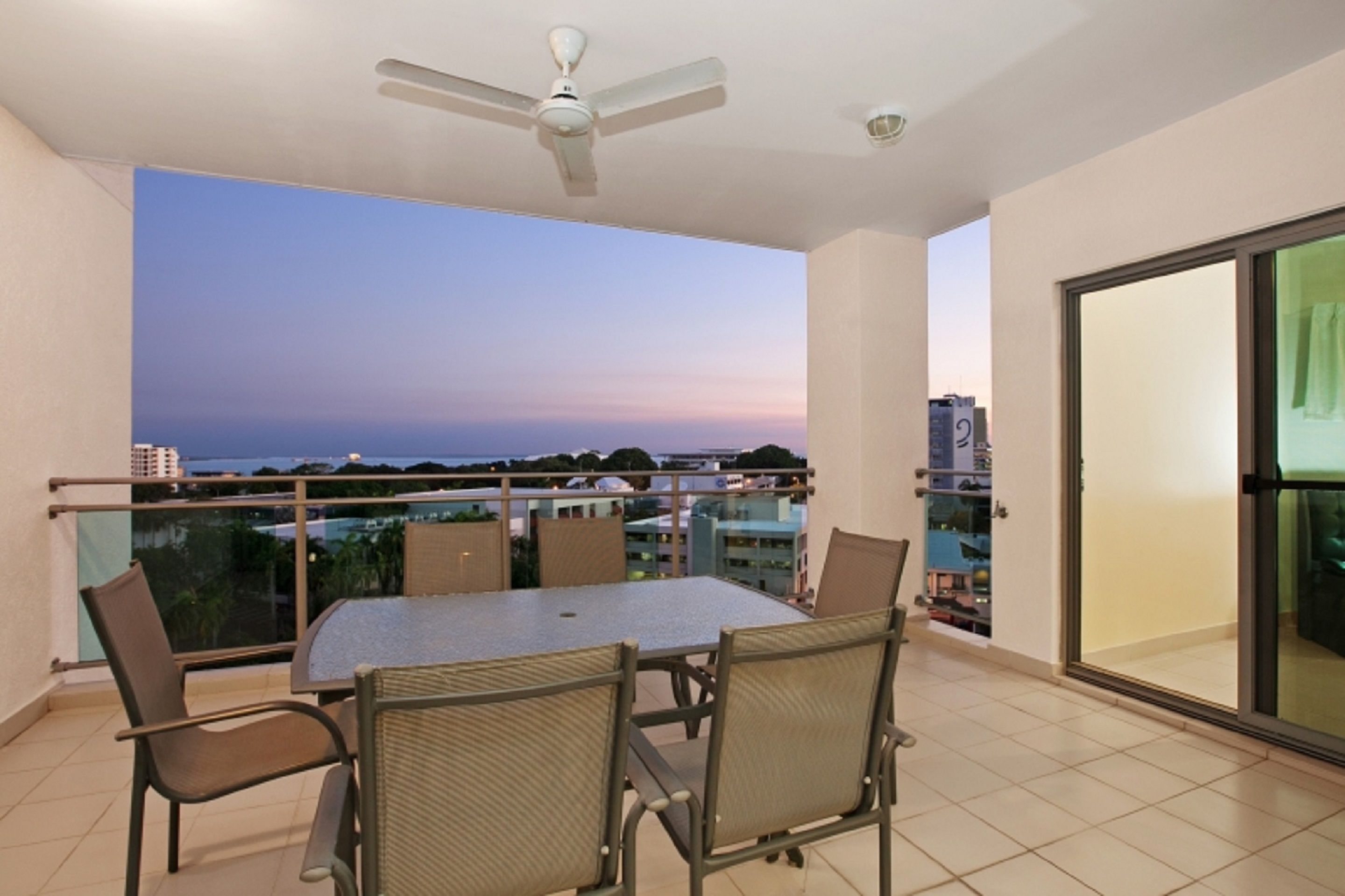Un balcon avec une table et des chaises, un ventilateur de plafond et une vue sur l’océan.