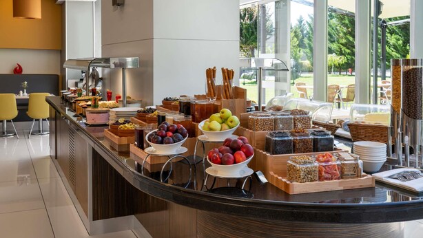 A breakfast buffet with various food items and a view of the outdoors. - ibis Kayseri (Kocasinan)