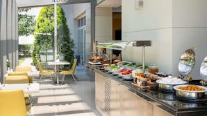 A modern dining area with a buffet setup, including various food items and a seating arrangement with yellow chairs. - ibis Kayseri (Kocasinan)