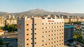A hotel with a flat roof, multiple floors, and a courtyard with outdoor seating.