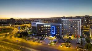 A hotel with a modern design, featuring a prominent 'Novotel' sign, a parking area, and a view of the surrounding cityscape. - ibis Kayseri (Kocasinan)