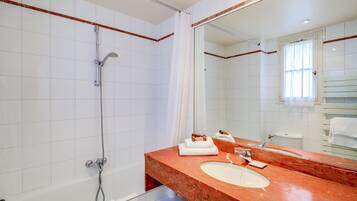 A bathroom with a white bathtub, a large mirror, and a marble sink.