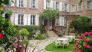 Un patio con un camino de piedra, un pequeño jardín y una mesa con sillas.