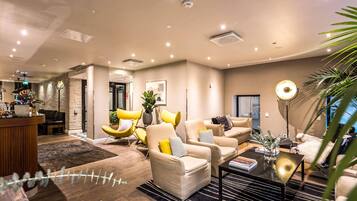 Una sala de estar moderna con sofás color beige, sillones amarillos y una mesa de centro.