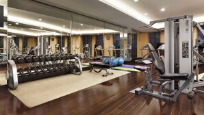 Une salle de sport moderne équipée de divers appareils d’exercice, notamment des haltères, un banc et des appareils de cardio.