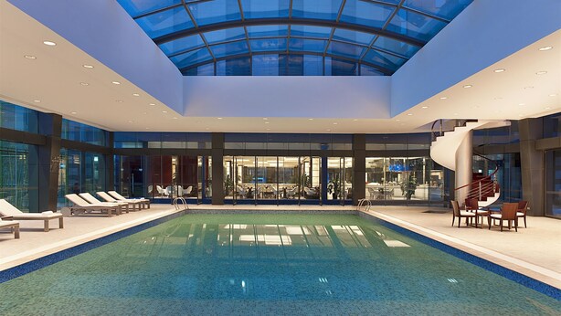 Une piscine intérieure dotée de chaises longues et d’un plafond en verre.