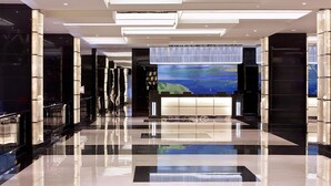 Un hall d’hôtel moderne avec un sol réfléchissant, un grand écran numérique affichant un paysage et un design de plafond contemporain.