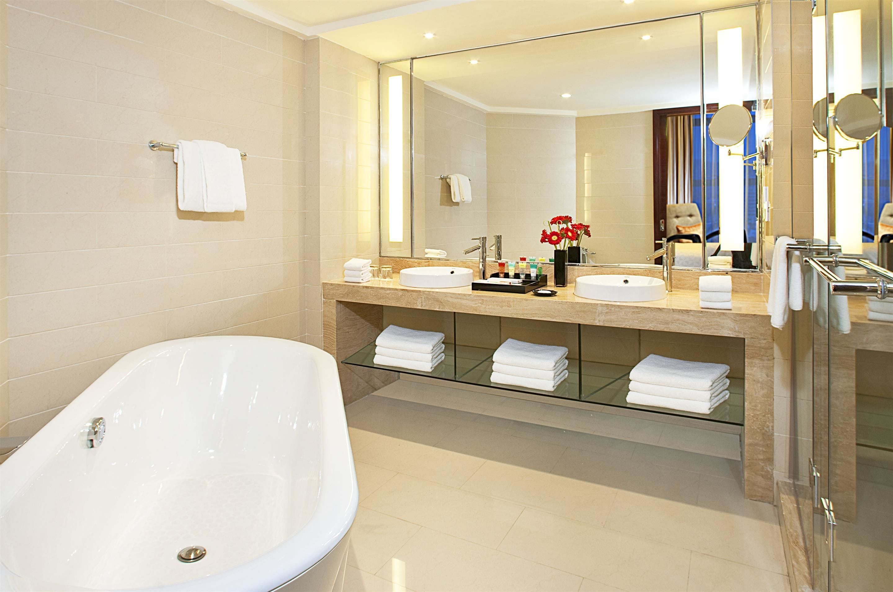 A modern bathroom with a freestanding bathtub, a large mirror, and a vanity with a sink and countertop.