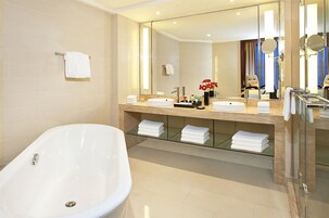 Un baño moderno con una bañera independiente, un espejo grande y un tocador con lavabo y encimera.