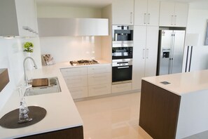 Une cuisine moderne avec des meubles blancs, des appareils en acier inoxydable et un îlot central.