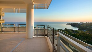 Un balcon doté d’une balustrade en verre offrant une vue sur la côte.