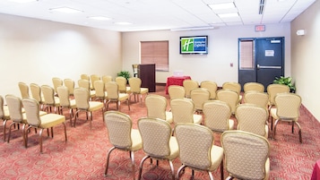 A conference room with rows of chairs, a podium, and a Holiday Inn Express sign.