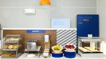 A bakery counter with various baked goods, a toaster, and a sign that reads 'THIS IS HOW WE ROLL'.