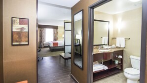 A hotel room with a bed, a desk, a chair, a bathroom with a sink, mirror, and toilet. - Holiday Inn Express & Suites Elkton - University Area by IHG (Elkton)