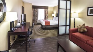 A hotel room with a bed, desk, chair, and a sofa. - Holiday Inn Express & Suites Elkton - University Area by IHG (Elkton)