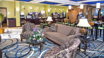 A hotel lobby with a seating area, a reception desk, and a food service counter.