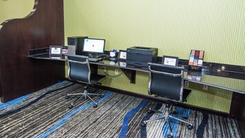 Un salón de conferencias de hotel con un escritorio, dos sillas, una computadora y un teléfono.