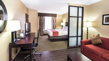 Una habitación de hotel con escritorio, cama, sofá y televisión.