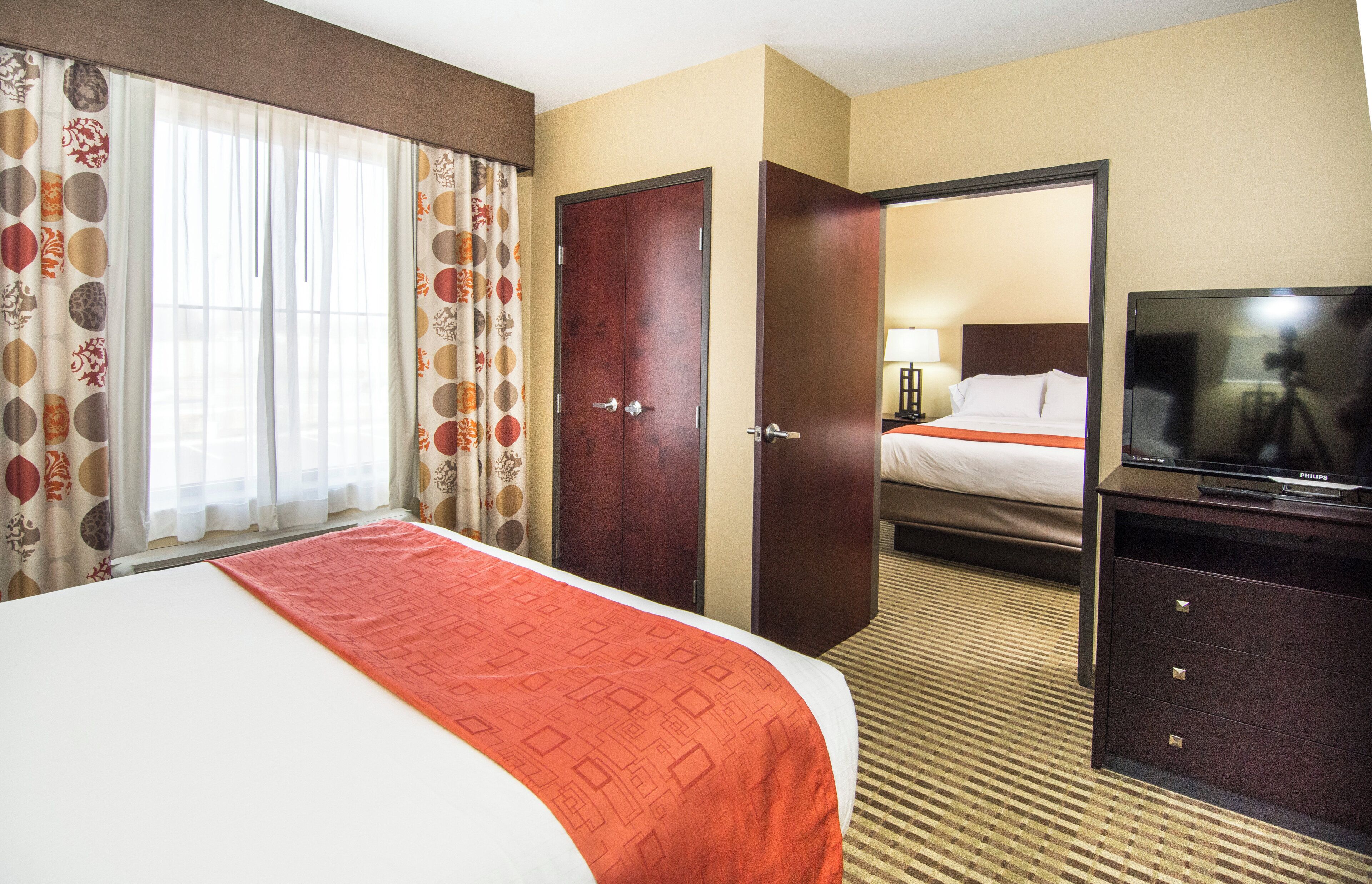 A hotel room with a bed, a television, a desk, and a wardrobe.