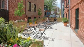 A courtyard with outdoor seating, brick buildings, and potted plants. - Hotel Brexton, Trademark Collection by Wyndham (Baltimore)