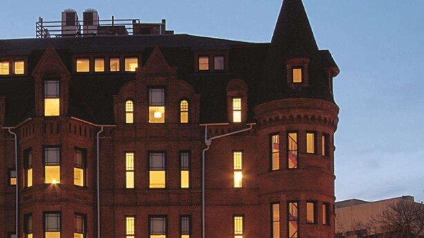A large, multi-story building with a prominent turret and arched windows. - Hotel Brexton, Trademark Collection by Wyndham (Baltimore)