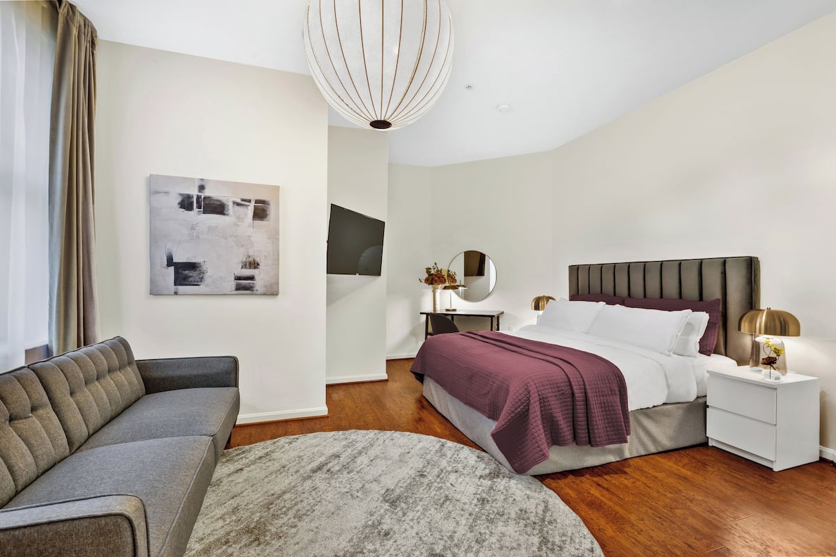Ein modernes Schlafzimmer mit Bett, Nachttisch und einer Couch.